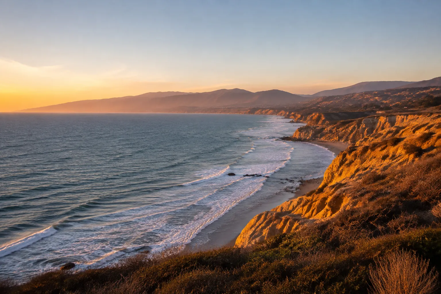 Coastline with cliffs, surf and mountains at sunset